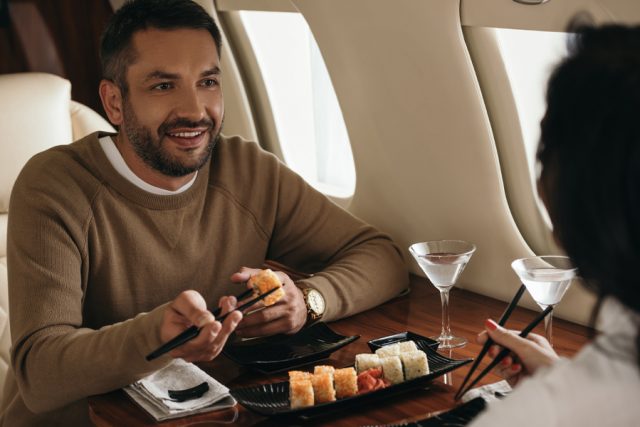 Two people eating sushi on a plane