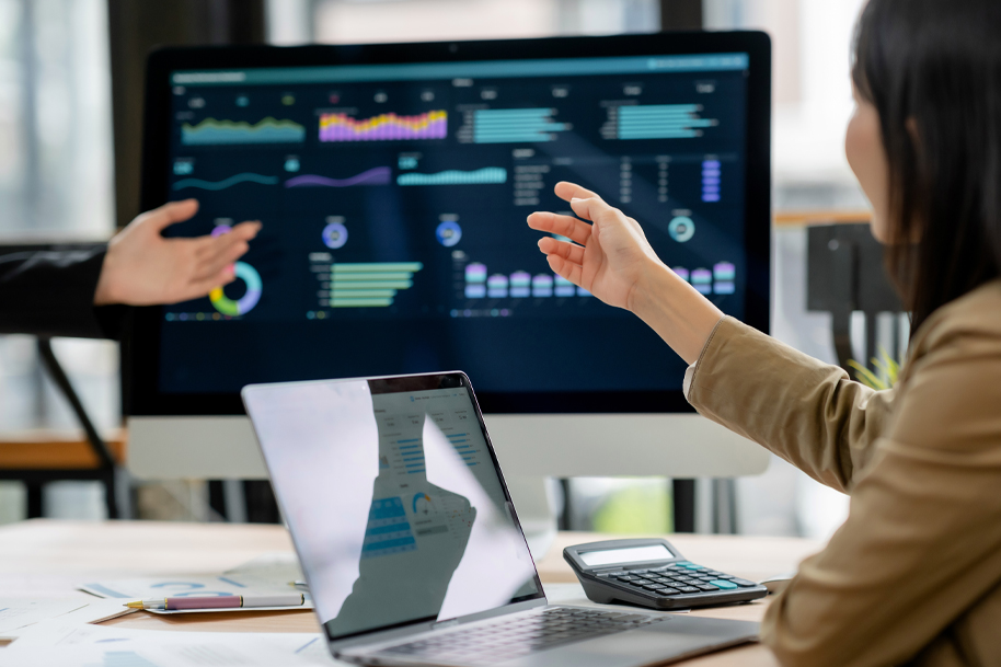 Two people looking at information on screen and laptop