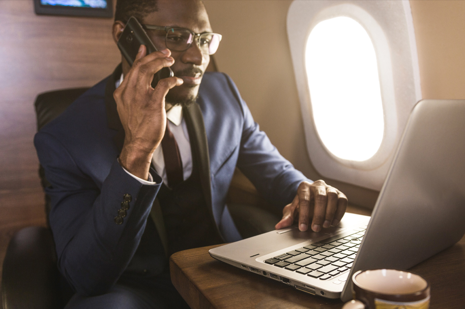 Man in a private jet talking on phone and using a laptop